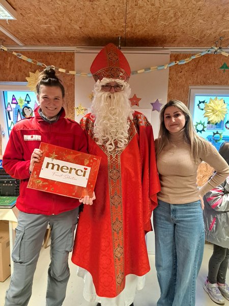 Der Nikolaus mit zwei Mitarbeiterinnen des Flussbauhofes an seiner Seite. Die Mitarbeiterin links von ihm hält eine große Tafel Merci-Schokolade.