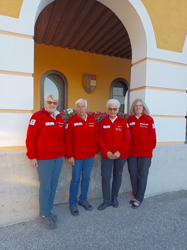 Seniorenbetreuerin stehen vor Gebäude in Rotkreuz-Uniform