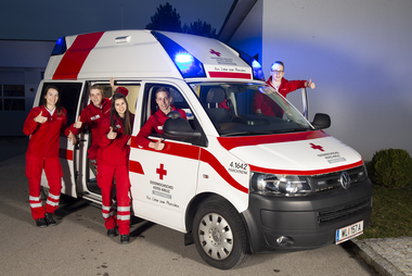© TAF Photography Sanitäterinnen und Sanitäter stehen in, neben und auf einem Rettungsauto
