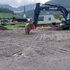 Bagger auf einem Baugrundstück mit Kirche Wiesing im Hintergrund