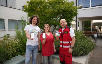 3 Mitarbeiterinnen des Roten Kreuzes zeigen ihre Handys mit der App