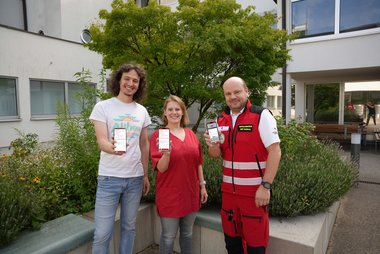 3 Mitarbeiterinnen des Roten Kreuzes zeigen ihre Handys mit der App
