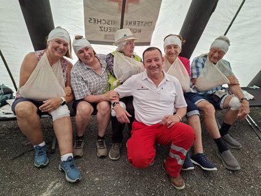 Erste-Hilfe-Kursteilnehmer:innen mit Rettungssanitäter:innen.