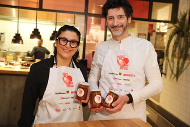 Eine Köchin und ein Koch halten Gulasch im Glas in der Hand