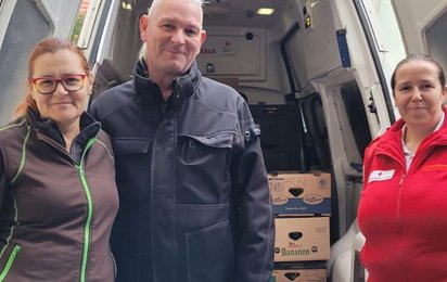 Das Ehepaar Warter steht vor einem Rotkreuz-Wagen, gemeinsam mit einer Rotkreuz-Mitarbeiterin und einer symbolischen Kiste Paprika