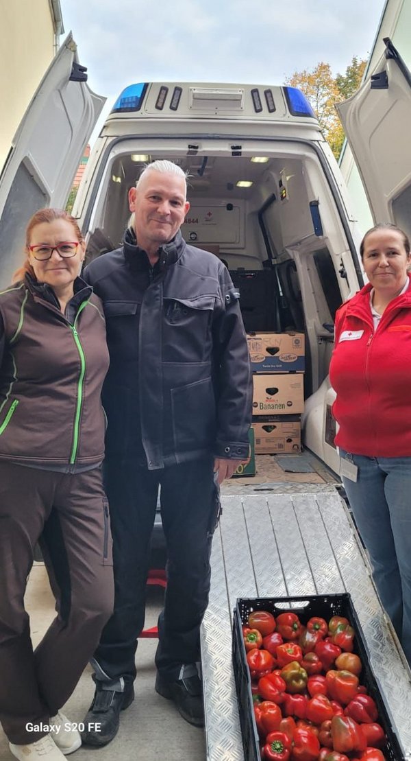 Das Ehepaar Warter steht vor einem Rotkreuz-Wagen, gemeinsam mit einer Rotkreuz-Mitarbeiterin und einer symbolischen Kiste Paprika