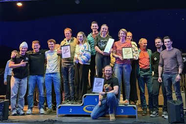 Foto von der Siegerehrung der Gesamtwertung nach Landesverbänden: Vertreterinnen der Mannschaften aus Tirol (1. Platz), Vorarlberg (2. Platz) und Salzburg (3. Platz) stehen auf und um das Siegerpodium.