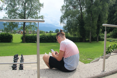 Ein Jugendlicher sitzt alleine mit seinem Handy im Park
