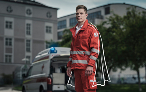 Ein Zivildiener steht vor einem Rettungswagen und blickt in die Kamera. Ihm wurde ein Cape dazu gezeichnet, um ihn so als Helden darzustellen.