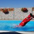 Person in Rotkreuz Uniform macht Sprung in einem Pool an einem heißen Sommertag