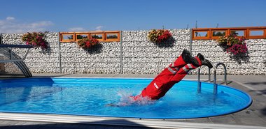 Person in Rotkreuz Uniform macht Sprung in einem Pool an einem heißen Sommertag
