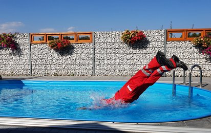Person in Rotkreuz Uniform macht Sprung in einem Pool an einem heißen Sommertag