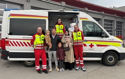 Das Rettungsteam des Roten Kreuzes besuchte Inaya und ihre Familie. (v.l.n.r.): Rettungssanitäter Matthias, Elias, Papa Abubakar, Rotkreuz-Helferin Franziska, Hanni, Mama Hiba mit Baby Inaya, Rettungssanitäter Martin Friedl.