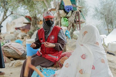 Rotkreuzhelferin in Uniform in Afganistan sitzt Frau gegenüber