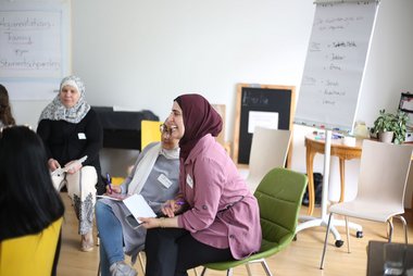 eine Runde von Frauen sitzt in einem Raum zusammen und unterziehen sich einer Schulung zum Thema richtig argumentieren