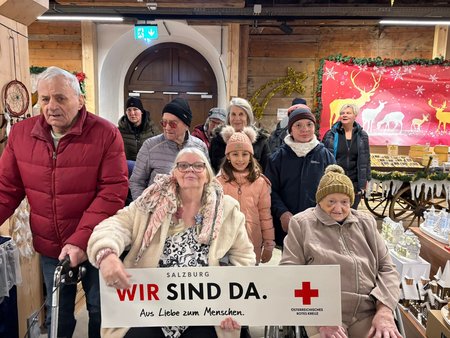 Eine Gruppe mit Pflegekräften und Bewohner:innen des Seniorenwohnhauses Hallein am Christkindlmarkt.