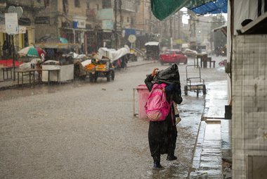 Frau mit Kind bei starkem Regen auf Strasse in Gaza.