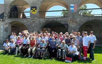 Eine Gruppe des Betreuten Reisen vom Roten Kreuz Waidhofen/Thaya anlässlich einer Reise auf einer Wiese vor einem historischen Gebäude.