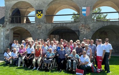 Eine Gruppe des Betreuten Reisen vom Roten Kreuz Waidhofen/Thaya anlässlich einer Reise auf einer Wiese vor einem historischen Gebäude.