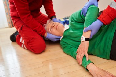 Eine Frau liegt am Fußboden und wird von Sanitätern versorgt.