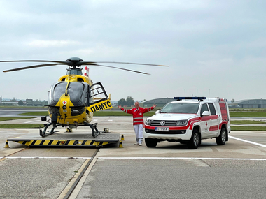 Leopold Hartl steht zwischen dem Notarzthubschrauber C10 und dem Notarzteinsatzfahrzeug