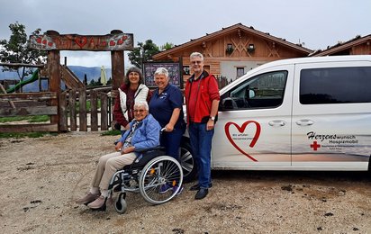Vier Personen vor dem Herzenswunsch-Hospizmobil auf der Tuff Alm in Südtirol
