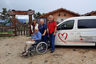 Vier Personen vor dem Herzenswunsch-Hospizmobil auf der Tuff Alm in Südtirol