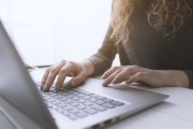 Woman sitting at desk and connecting with her laptop - © ©StockPhotoPro - stock.adobe.com Frau mit Notebook
