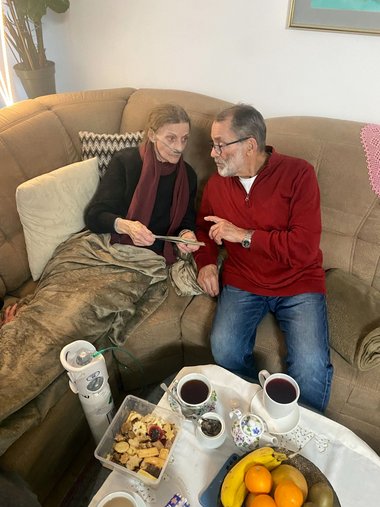 Margarete sitzt mit ihrem Bruder Alfred auf dem Sofa und sieht sich Fotos an