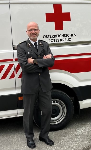Ein Mann steht mit verschränkten Armen vor einem Rettungswagen