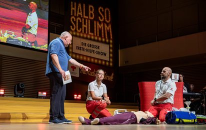 2 Notfallsanitäter erklären die Reanimation mit Hilfe einer Reanimationspuppe