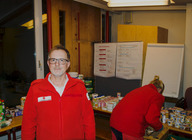 Michael Wutz - Leiter der Team Österreich Tafel - steht vor zu verteilenden Lebensmitteln. Im Hintergrund sortiert eine Mitarbeiterin gerade einige Lebensmittel.