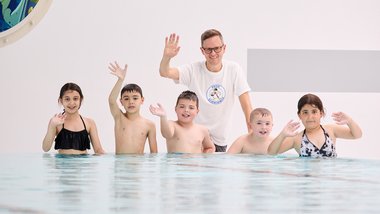 Landesschwimmreferent Michael Heilbrunner besuchte einen Schwimmkurs in Wels. Man sieht Kinder und den Schwimmlehrer im Hallenbad.