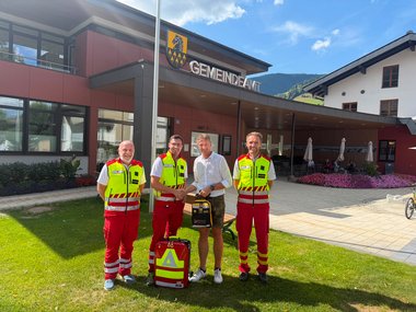 Drei Rotkreuz-Mitarbeiter stehen gemeinsam mit dem Bürgermeister von Niedernsill vor dem Gemeindeamt