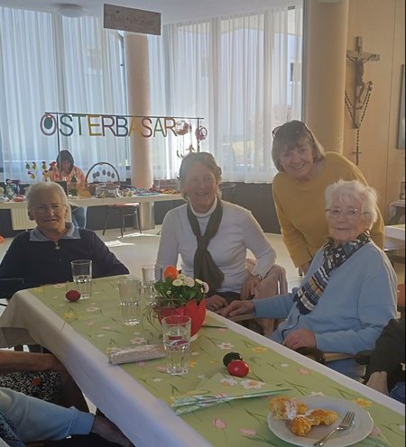 Bewohner:innen und Besucher:innen sitzen am österlich dekorierten Tisch