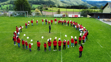 Jugendrotkreuzkinder stehen im Kreis mit je einem weißen Luftballon in der Hand