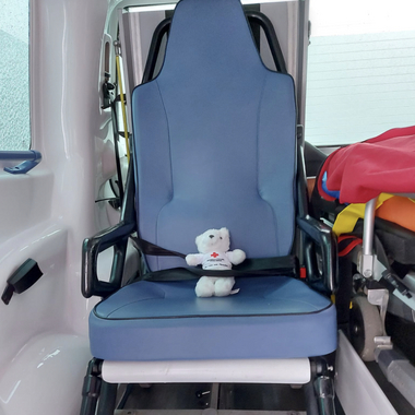 Zu sehen ist Bärli, der in einem blauen Tragstuhl eines Rettungswagens angeschnallt sitzt. Der Patient:innenraum des Rettungswagens ist der hauptsächliche Arbeitsplatz unserer Zivis nach ihrer Rettungssanitäter-Prüfung.