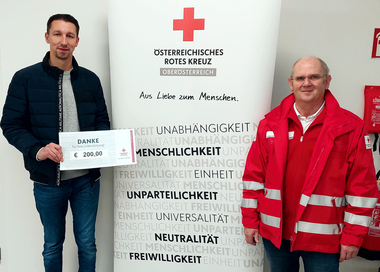 Admir Hodzic übergibt Rotkreuz-Markt-Mitarbeiter Franz Mair Warengutscheine