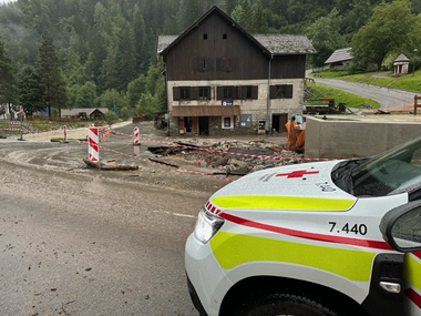 Rotes Kreuz Auto vor Haus und Straße mit Hochwasserschäden in Kärnten