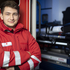 Ein Zivildiener steht mit verschränkten Händen vor einem Rettungsauto.