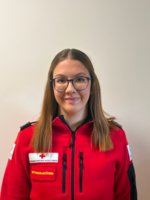 Jasmin Kober in weißem Rotkreuz-Polo vor unscharfem grauen Hintergrund.
