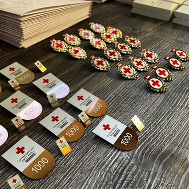 Zu sehen sind einige Rotkreuz-Orden und Auszeichnungen auf einem Holztisch.