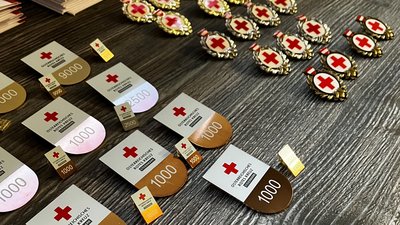Zu sehen sind einige Rotkreuz-Orden und Auszeichnungen auf einem Holztisch.