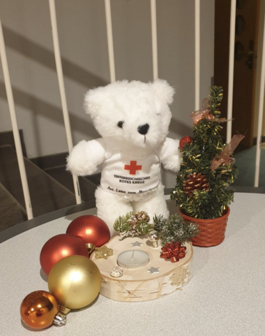 Zu sehen ist Bärli mit Christbaumkugeln und einem Mini-Christbaum.