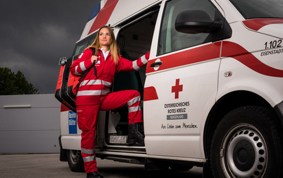 © ÖRK / LV Burgenland / Daniel Neubauer Eine junge Sanitäterin steht in der Tür eines Rettungsautos. Am Rücken trägt sie einen Notfallrucksack.