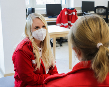 Das Bild zeigt Johanna im Gespräch über die Erfahrungen eines belastenden Einsatzes mit einer Kollegin aus dem Rettungsdienst.