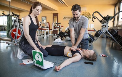 Erste Hilfe wird geleistet von 2 Personen in einem Fitnessstudio