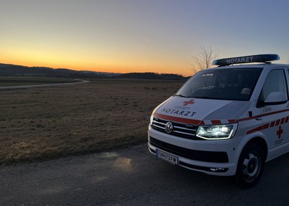 Ein Notarzteinsatzfahrzeug (NEF) des RK Waidhofen/Thaya steht im Sonnenaufgang.