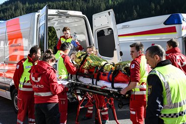 Einsatzkräfte schieben einen Patienten auf einer Trage in einen Rettungswagen.