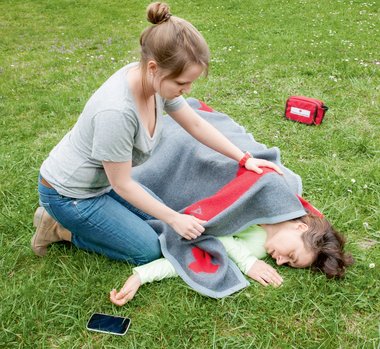 Eine Frau kümmert sich um eine Person die am Boden liegt.